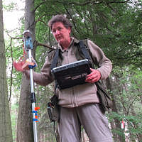 Mitarbeiterin bei der Datenerhebung mit Messinstrument im Wald