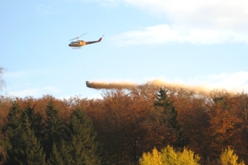 Foto mit Hubschrauber, der Kalk im Wald ausbringt