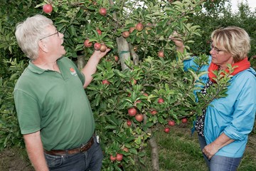 Ministerin Barbara Otte-Kinast und ein Obstbauer stehen an einem Apfelbaum.