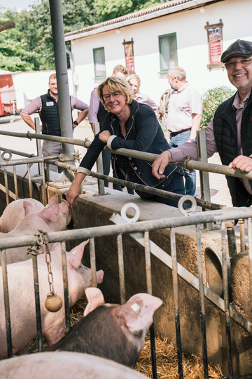 Ministerin Barbara Otte-Kinast steht vor einem Stall, in dem Schweine auf Stroh gehalten werden.