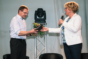 Ministerin Barbara Otte-Kinast überreicht dem Zweitplatzierten einen Blumenstrauß und eine Trophäe