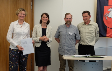 Ministerin Miriam Staudte mit Projektverantwortlichen bei der Übergabe des Förderbescheids