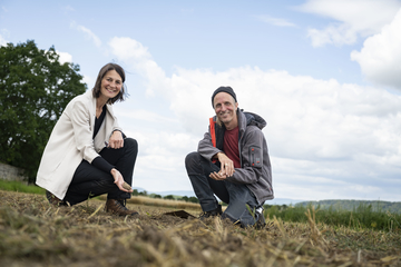 Ministerin Miriam Staudte und Landwirt Jan Wittenberg hocken auf einem Acker.