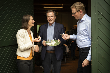 Ministerin Staudte und Henning Müller probieren jeweils ein Stück Käse, Ralf Hinrichs hält einen Teller mit den Produkten.