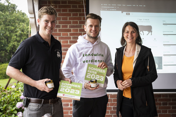 Henrik Thieken und Moritz Armbrust halten ein Schild mit der Aufschrift "Sommerreise 2023" in der Hand, daneben steht Ministerin Miriam Staudte.