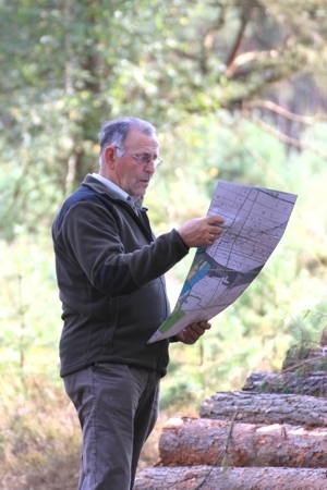 Foto eines Waldbesitzers mit Betriebskarte an einem Holzpolter
