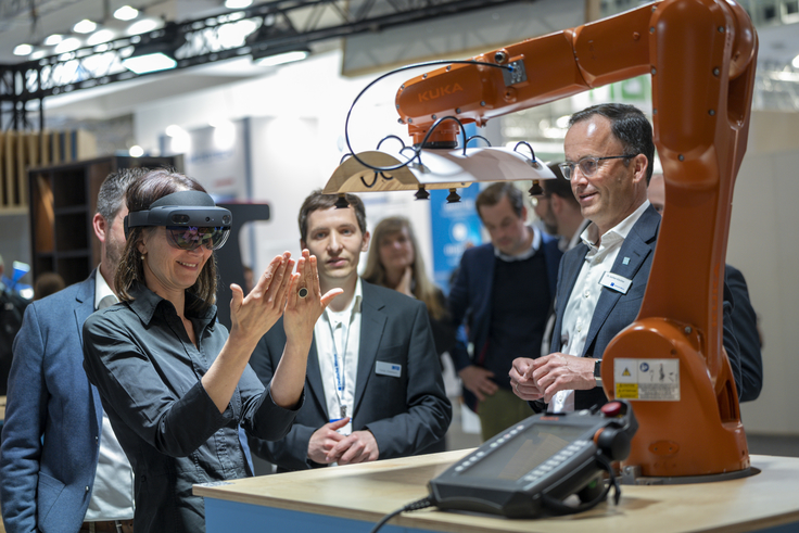 Ministerin Miriam Staudte mit einer Augmented Reality-Brille vor einer Maschine.