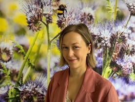 Junge Frau vor einem Bild mit blauen Blüten