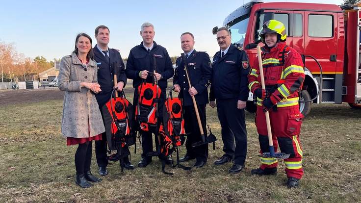Ministerin Miriam Staudte (1 v. l.) übergibt gemeinsam mit dem Präsident des LFV-NDS Olaf Kapke (5 v. l.) die Löschrucksäcke und Waldbrandwerkzeuge an den Landkreise Heidekreis (2 v. l.), den Landkreis Lüneburg (3. v. l.) und den Landkreis Uelzen (