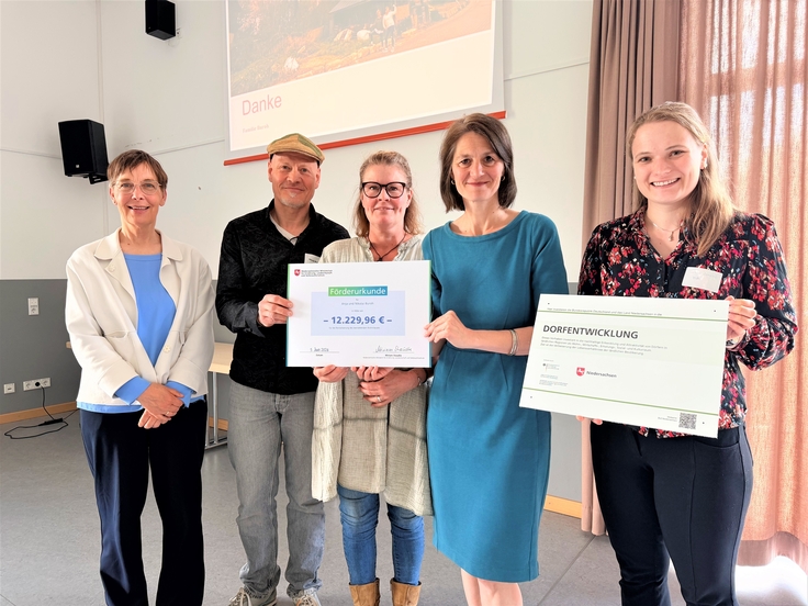 Ministerin Miriam Staudte (4. v. l.) übergibt eine Förderurkunde für die Revitalisierung eines leerstehendes Wohnhauses.