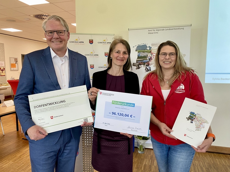 Ministerin Miriam Staudte (mitte) übergibt gemeinsam mit Nikolaus Jansen (Landesbeauftragter für regionale Landesentwicklung, links) en Förderbescheid für das Projekt "Umnutzung des Letas-Hauses", LK Ammerland