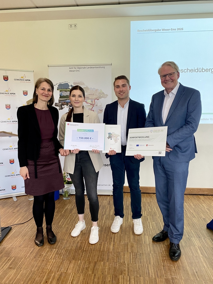 Ministerin Miriam Staudte (links) und Nikolaus Jansen (Landesbeauftragter für regionale Landesentwicklung, rechts) übergeben den Förderbescheid für das Projekt "Revitalisierung des alten Lehrerhauses", LK Osnabrück