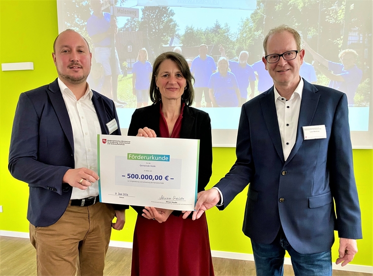 Ministerin Staudte (mitte) übergibt einen Förderbescheid für die Aufwertung der Kernzone in Hüde