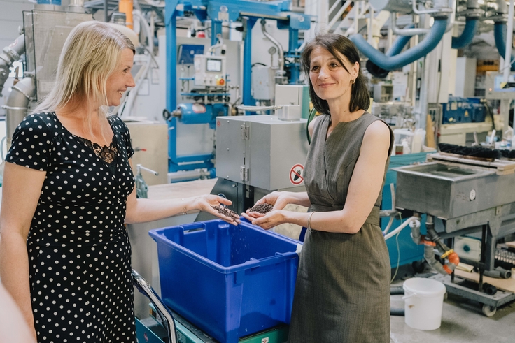 Ministerin Miriam Staudte (r.) lässt sich Produktionsschritte in einer Produktionshalle von einer blonden Frau erläutern