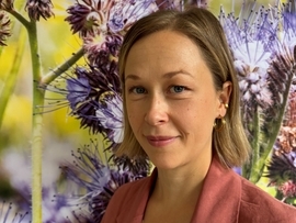 Junge Frau mit langen blonden Haaren vor Blumen-Hintergrund