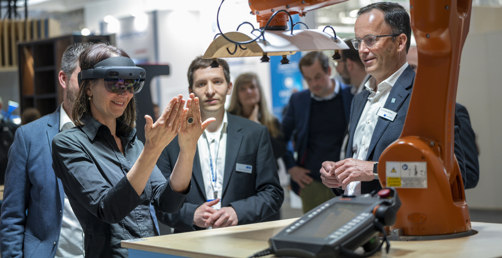 Ministerin Miriam Staudte mit einer Augmented Reality-Brille vor einer Maschine.