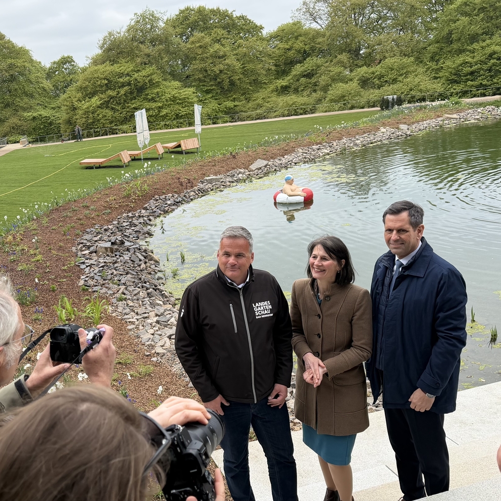 Landwirtschaftsminsiterin Miriam Staudte steht mit Ministerpräsident Olaf Lies und Stadxtdirektor Mike Schmidt in Bad Nenndorf vor einem anlegeten See auf dem Gelände der Landesgartenschau 2026