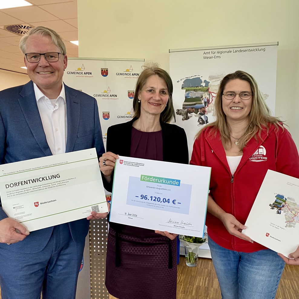 Ministerin Miriam Staudte (mitte) übergibt gemeinsam mit Nikolaus Jansen (Landesbeauftragter für regionale Landesentwicklung, links) en Förderbescheid für das Projekt "Umnutzung des Letas-Hauses", LK Ammerland