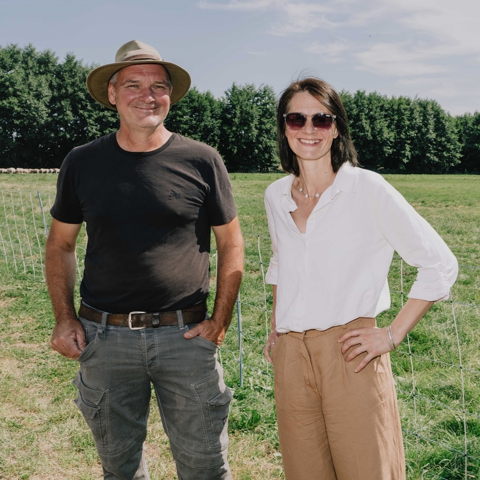 Ein Foto der Sommertour 2026: Ministerin Miriam Staudte mit Deichschäfer Stefan Erb auf einer Wiese, Schafe im Hintergrund