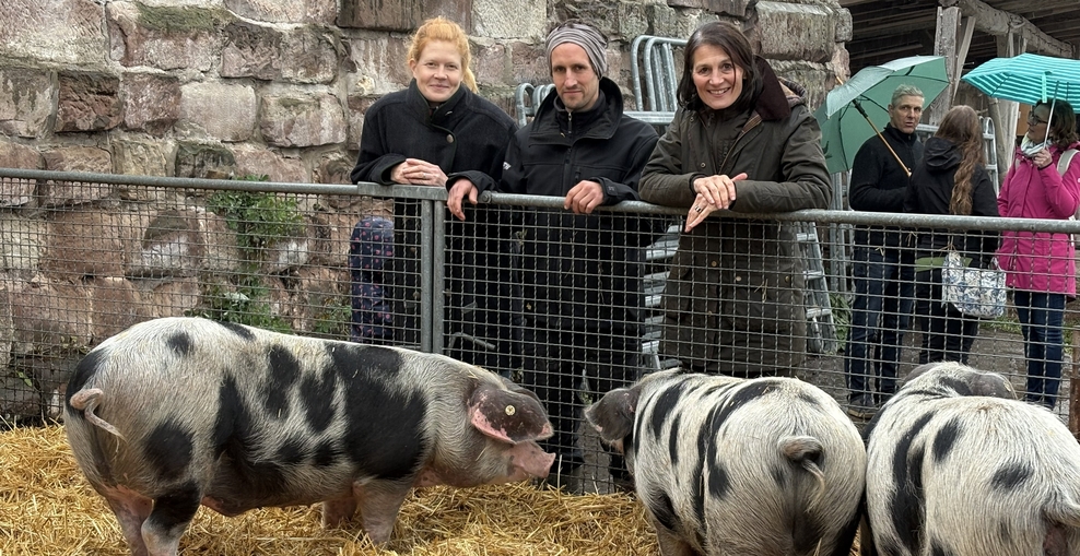Ministerin Staudte (rechts) mit dem Betriebsleiter-Paar Katharina und Till Theato bei den Bunten Bentheimer Schweinen des Brothofs Waake.